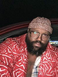 a man with glasses and a beard sitting in a car